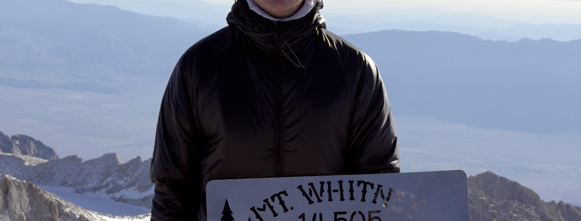 Menold standing atop Mt Whitney on a sunny day